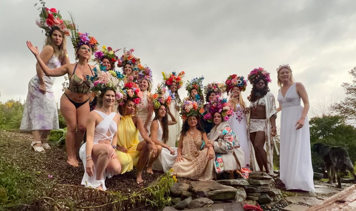 The women of the Goddess Gathering on a hillside in towering flower crowns