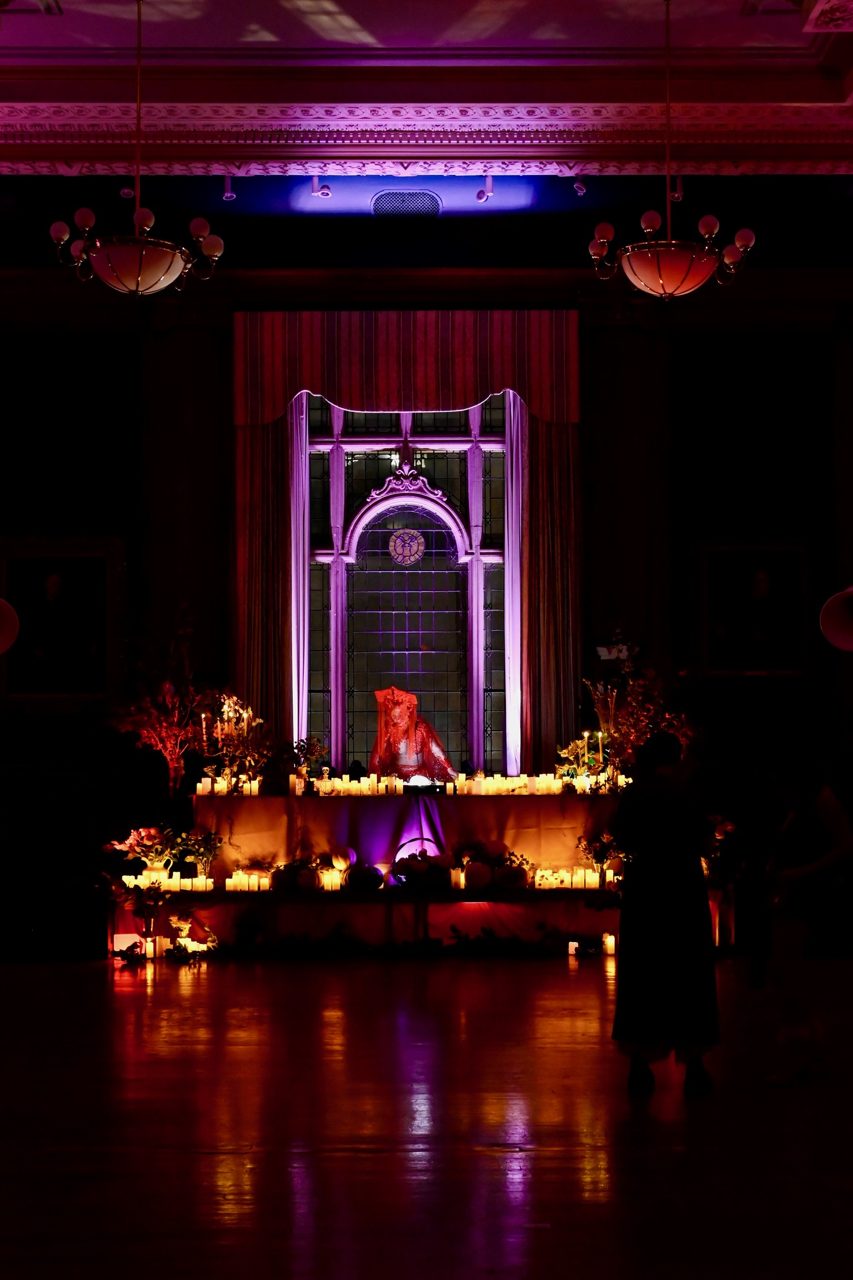The hall at the Mütter Museum: a lit archway and candles glowing at the far end of a dark floor